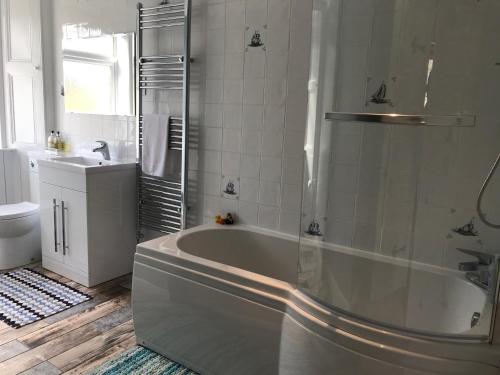 a white bathroom with a tub and a sink at Carrick Farm in Lochgoilhead