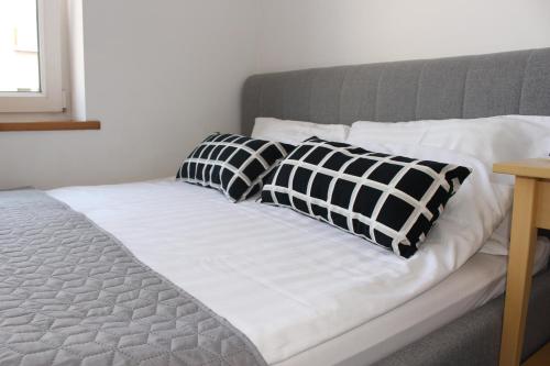 a bed with black and white pillows on it at Apartament Targ Rybny LUXON Gdansk in Gdańsk