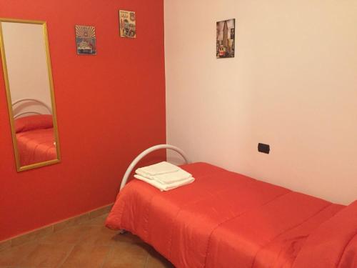 um quarto vermelho com uma cama e um espelho em Corraleddu apartments em Dorgali