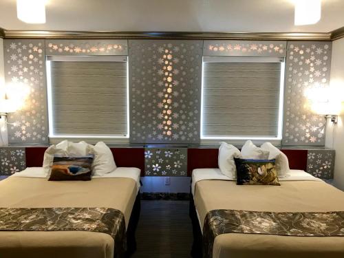 two beds in a room with two windows at Lake View Suites in West Yellowstone