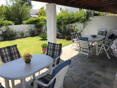 un patio con 2 mesas y sillas y un jardín en Porto Hydra, en Ermioni