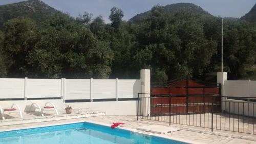 a swimming pool with two chairs and a fence at Villa Fedrita in Acharavi