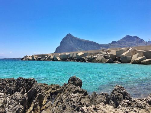 a rocky shore with blue water and mountains in the background at Albergo Ristorante Saverino in Valderice