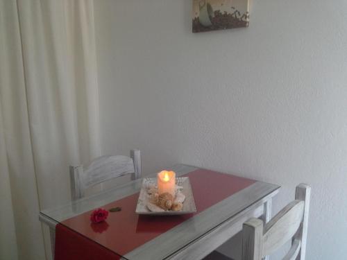 a candle sitting on a red table with white chairs at Kiklamino Sunset Studios in Oia
