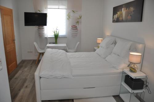 a white bedroom with a white bed and a desk at Gästezimmer Resi in Illmitz