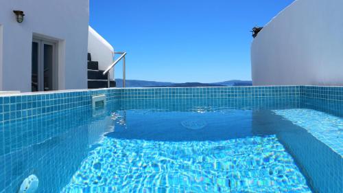 a swimming pool with a blue tiled floor and a building at Aqua & Terra Traditional Cave Houses in Oia