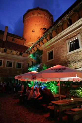 a group of people sitting under an umbrella in front of a building at Zamek Reszel in Reszel