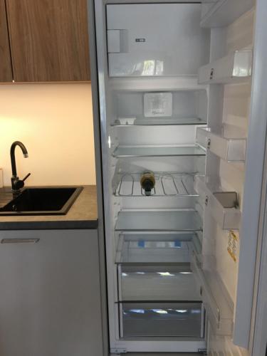 an empty refrigerator with its door open in a kitchen at Studio 33 z Ogrodem in Pogorzelica