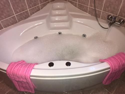 a bath tub filled with water with a pink towel at Apartman EXCLUZIV in Prijedor