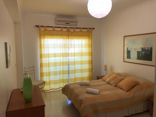 um quarto com uma cama grande e uma janela em Algarve Armacao de Pera Alporchinhos Appartement Climatise Plage A Pied em Armação de Pêra