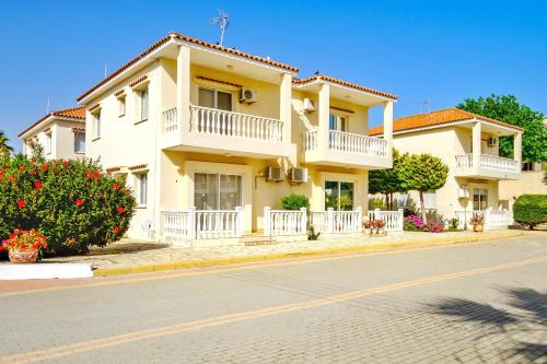 a large yellow house with balconies on a street at Hadjios Valley in Mazotos