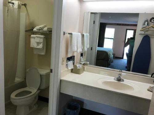 a bathroom with a sink and a toilet and a mirror at Clairmont Inn & Suites - Warren in Warren