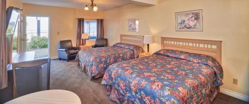 a hotel room with two beds and a chair at Black Sea Motel in Penticton