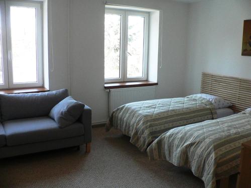 a bedroom with two beds and a chair and windows at Penzion Speller in Vysoký Újezd