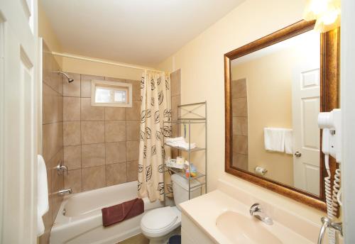a bathroom with a tub and a sink and a toilet at Black Sea Motel in Penticton