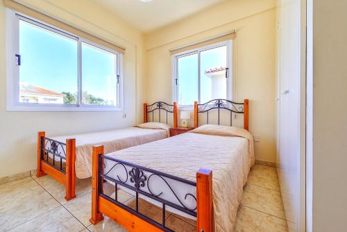 two beds in a room with two windows at Hadjios Valley in Mazotos