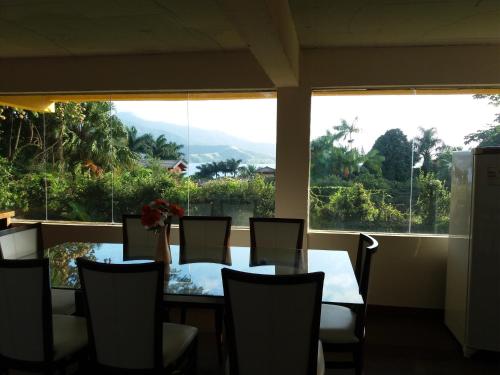 comedor con mesa y sillas y ventana grande en POUSADA TRUFFIMAR reservas Ilhabela, en Ilhabela