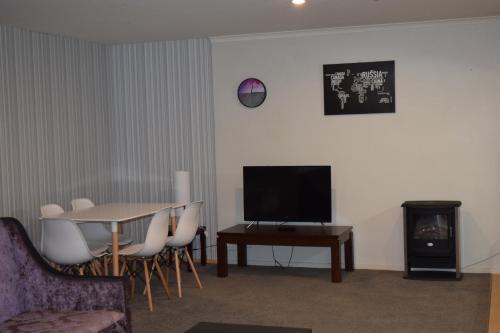 a living room with a table and a television at Silver Fern Lodge in Taupo
