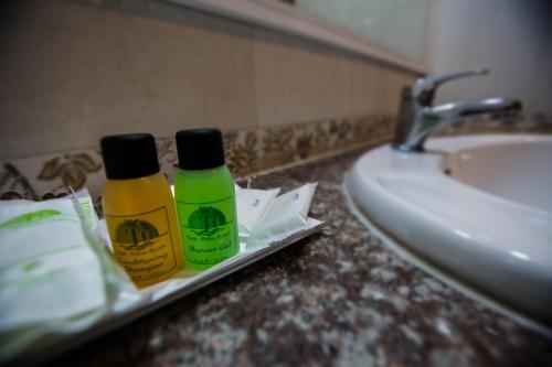 2 bouteilles de désinfectants sur un comptoir de salle de bains à côté d'un lavabo dans l'établissement Twin Palms Resort Pattaya, SHA Extra Plus Certified, à Pattaya