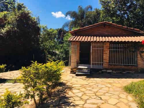 un pequeño edificio con una puerta en un jardín en Sitio Vale das Montanhas en São Thomé das Letras