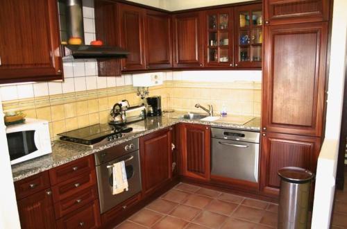 a kitchen with wooden cabinets and stainless steel appliances at Casa Rosa Azul - Terracos de Benagil (Cliffside) in Benagil