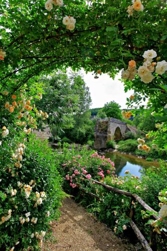 a garden with a bridge and flowers and a pond at Le Pont de L'Ouysse in Lacave