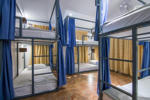 a room with four bunk beds with blue curtains at Bokre Angkor Hostel in Siem Reap