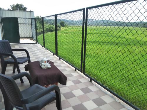 a patio with a table and chairs and a fence at Paddyfield Inn in Mananthavady
