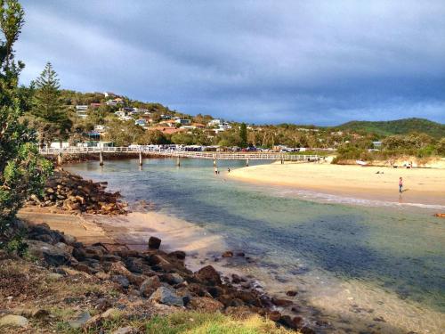 a beach with a pier and people in the water at Apollo 2 9 Hodgson Street in Crescent Head