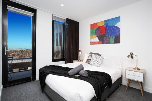 a bedroom with a bed and a large window at StayCentral - Northcote Hill Penthouse in Melbourne