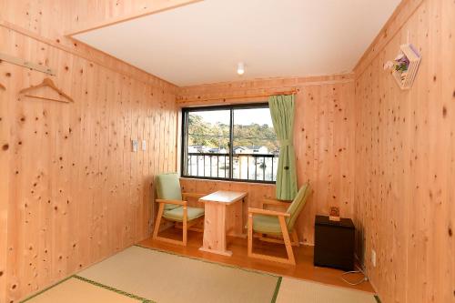 a room with a table and chairs and a window at Minshuku Nishidomari in Tsushima