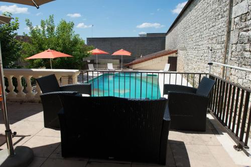 a swimming pool with chairs and umbrellas on a balcony at Logis Hôtel Vuillot in Cuiseaux
