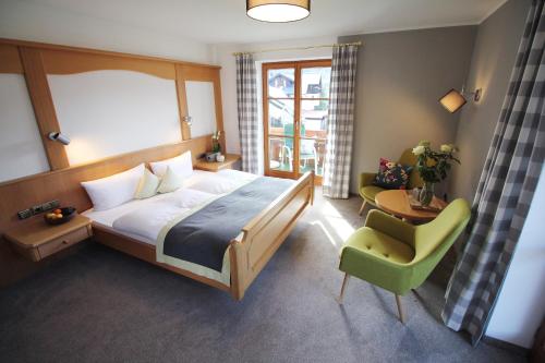 a bedroom with a bed and a green chair at Gästehaus Gaymann in Oberstdorf