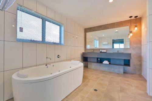 a bathroom with a tub and a large mirror at Best Western Plus North Lakes Hotel in North Lakes