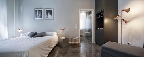 a white bedroom with a bed and a bathroom at Suite Vogue Stazione in Voghera
