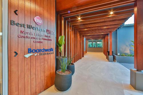 an office hallway with a sign on the wall and potted plants at Best Western Plus North Lakes Hotel in North Lakes
