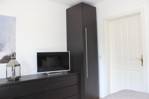 a bedroom with a black dresser with a tv on it at Ferienhaus an der Grenze zu Hamburg Zentrale Lage in Neu Wulmstorf