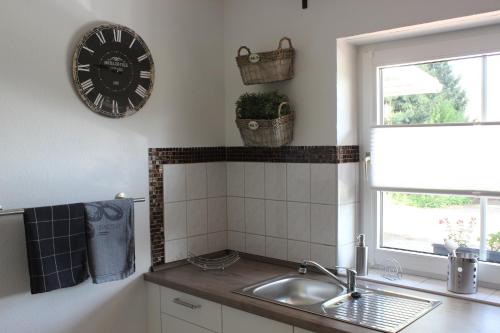 a kitchen with a sink and a clock on the wall at Ferienhaus an der Grenze zu Hamburg Zentrale Lage in Neu Wulmstorf
