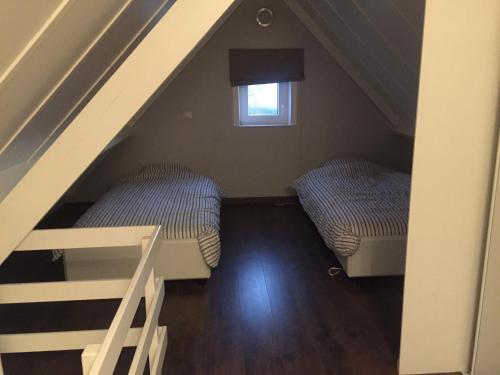 a attic room with two beds and a window at Nieuwendamme 88 in Nieuwpoort