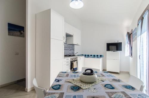 a white kitchen with a table with a tea pot on it at Case Vacanze La Pavoncella in Teulada