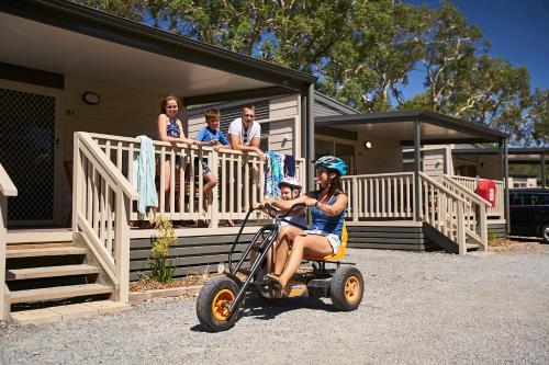a woman riding a mobility scooter in front of a house at Discovery Parks - Barossa Valley in Tanunda