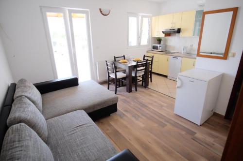 sala de estar con sofá, mesa y cocina en Apartmani Svemir, en Drage