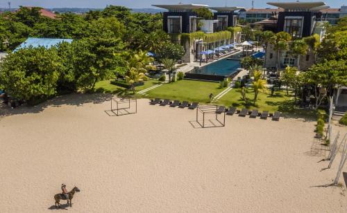 a dog standing on the beach in front of a resort at The Sakala Resort Bali All Suites in Nusa Dua