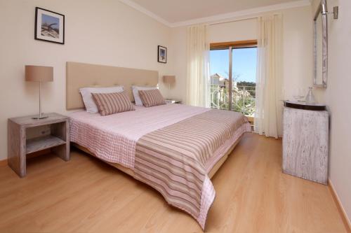 een slaapkamer met een groot bed en een raam bij Pinheiros da Balaia Villas in Albufeira