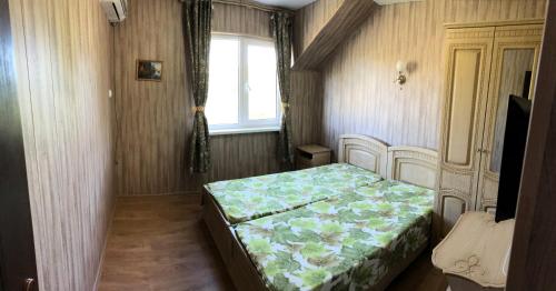 um quarto com uma cama num quarto com uma janela em Tsvietushchii sad em Sukko