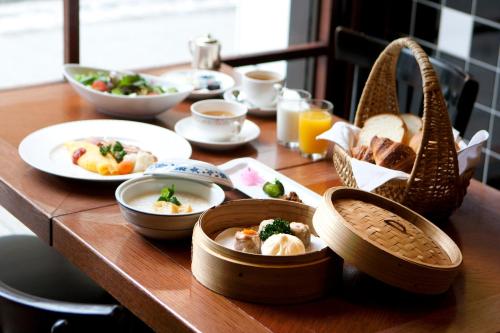 a wooden table with plates of food on it at Rose Hotel Yokohama, The Distinctive Collection By WORLDHOTELS in Yokohama