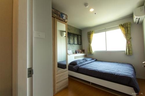 a small bedroom with a bed and a mirror at Lumpini LOFT condo 1705 in Ban Sahakham