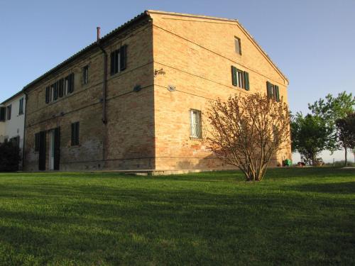 a large brick building with a tree in a field at B&B Cervare in Montelupone