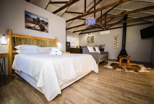 a bedroom with a large white bed and a couch at Reflections Guest Farm in Tulbagh