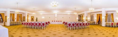 a banquet hall with red chairs and a table in it at Aurelius Imparatul Romanilor Hotel & SPA in Poiana Brasov
